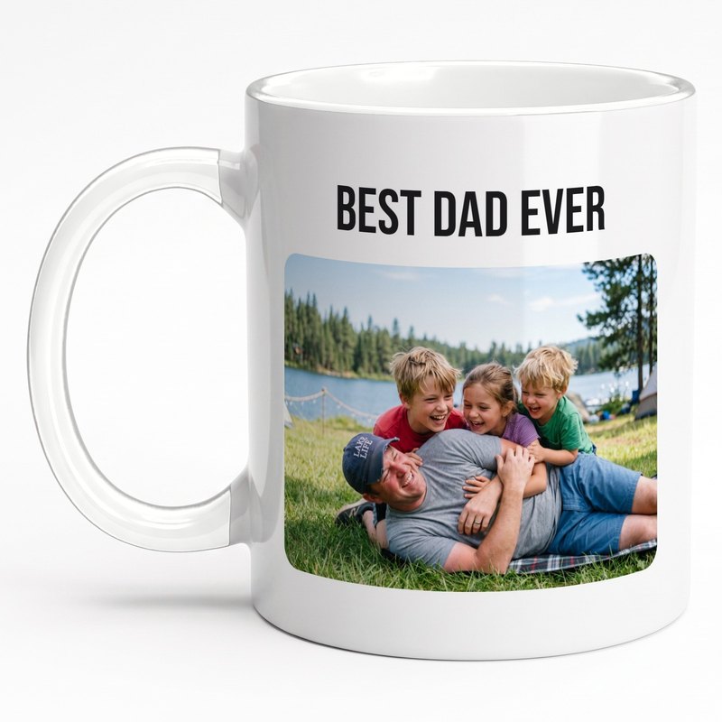 A white "Best Dad Ever" mug with three kids piling on their laughing dad at a lakeside campsite