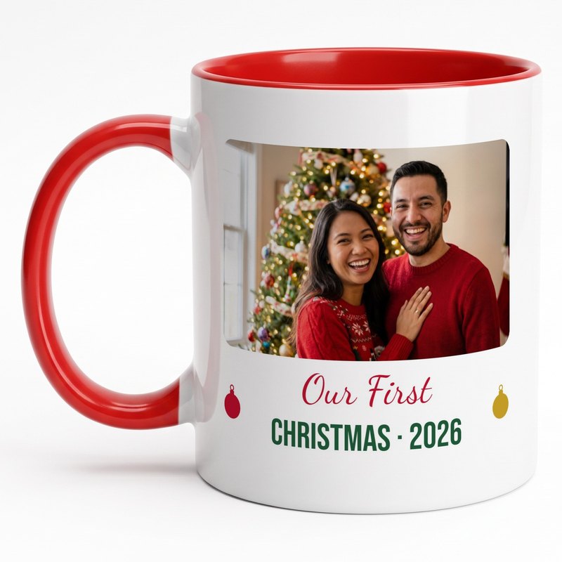 A red-rim "Our First Christmas 2026" mug with newlyweds in matching red sweaters by the tree